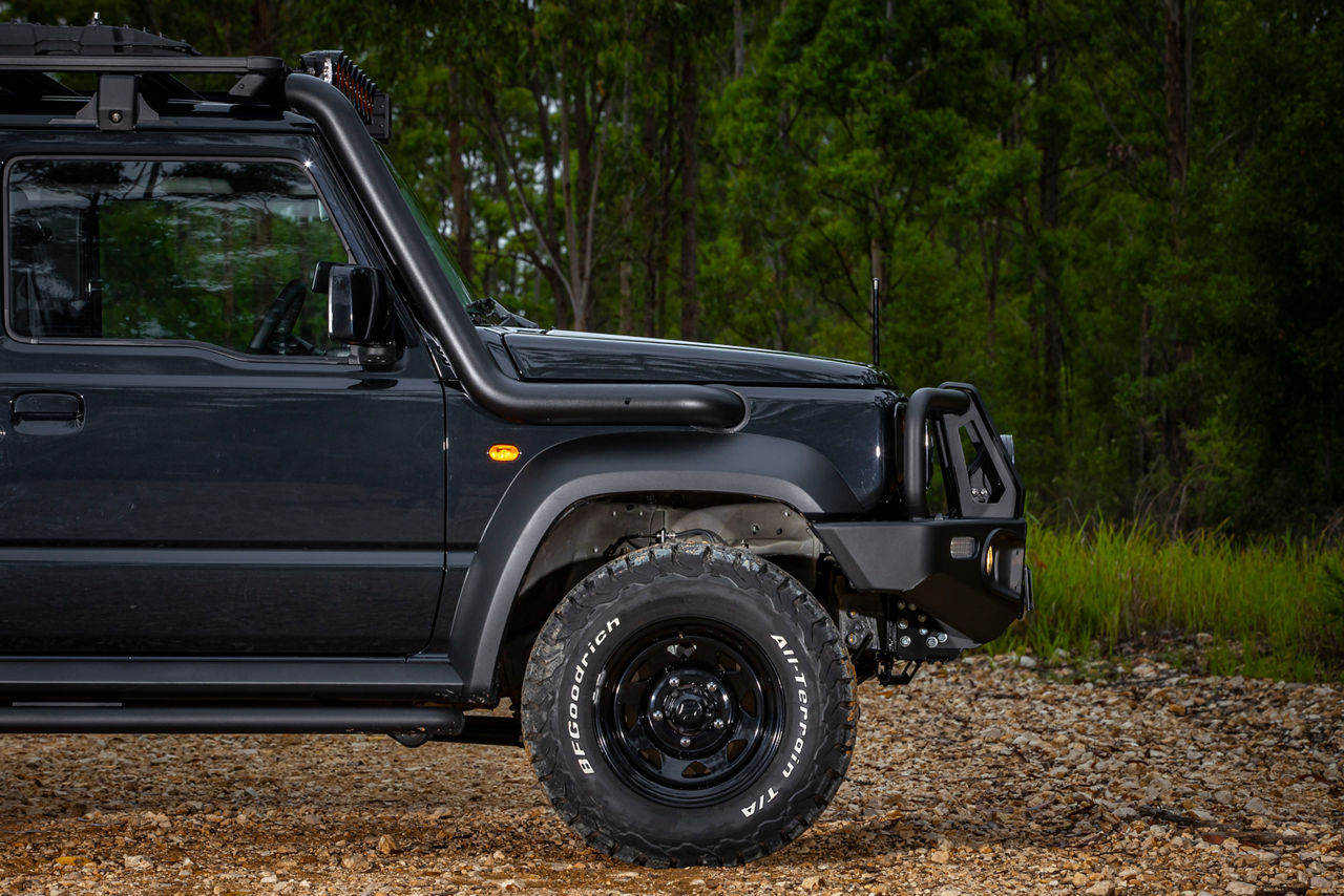 Close-up view of a Torqit snorkel fitted to a Suzuki Jimny in a forested off road environment.