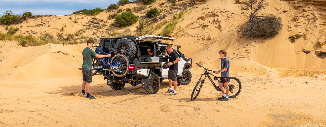Toyota HiLux 26 with a MITS Alloy tray, gear storage system and bicycles in a sandy off road environment.