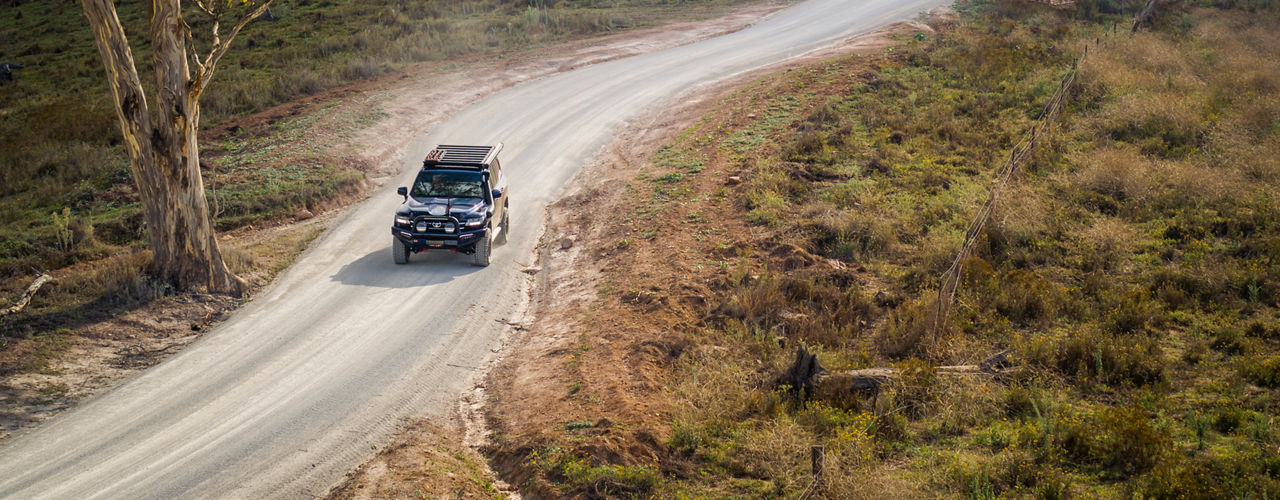 ARB equipped Toyota LandCruiser 300 Series touring along a winding country road in a rural landscape.