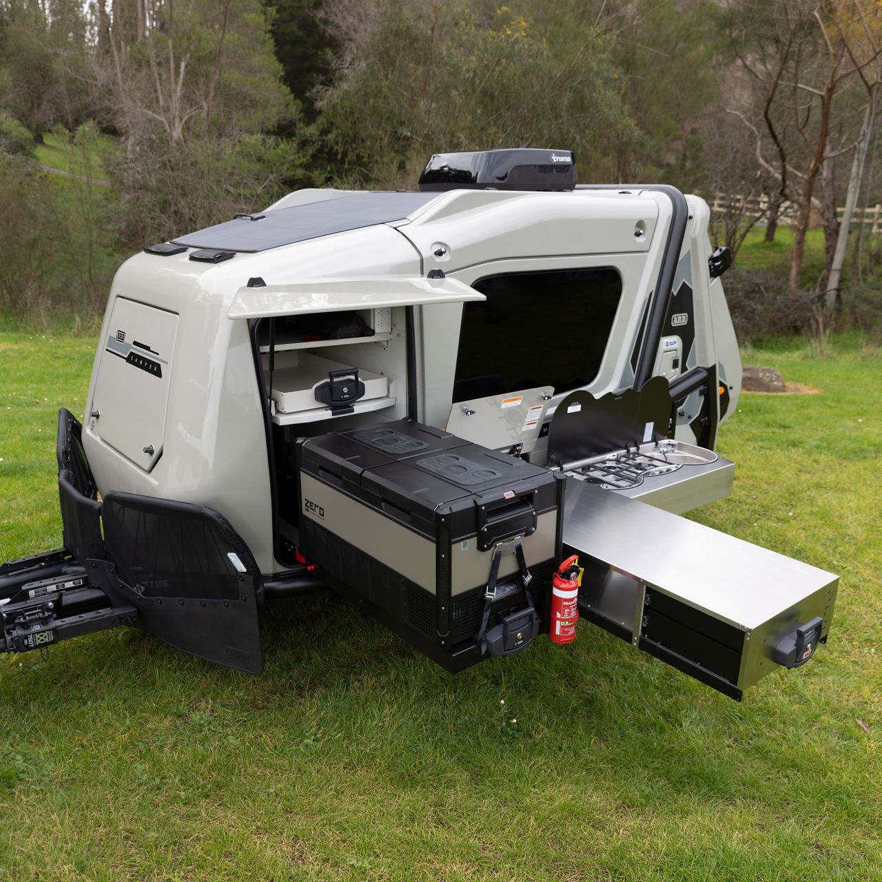 ARB Earth Camper GT with an external slide-out kitchen, fridge freezer and storage compartments deployed at a campsite.