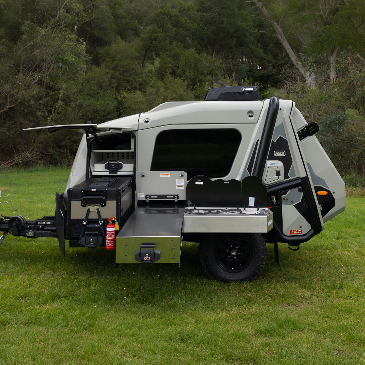 ARB Earth Camper GT with an external slide-out kitchen, fridge freezer and storage compartments deployed at a campsite.