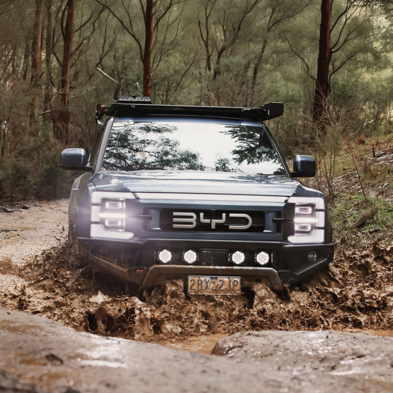 BYD Shark 6 on a muddy rural road.