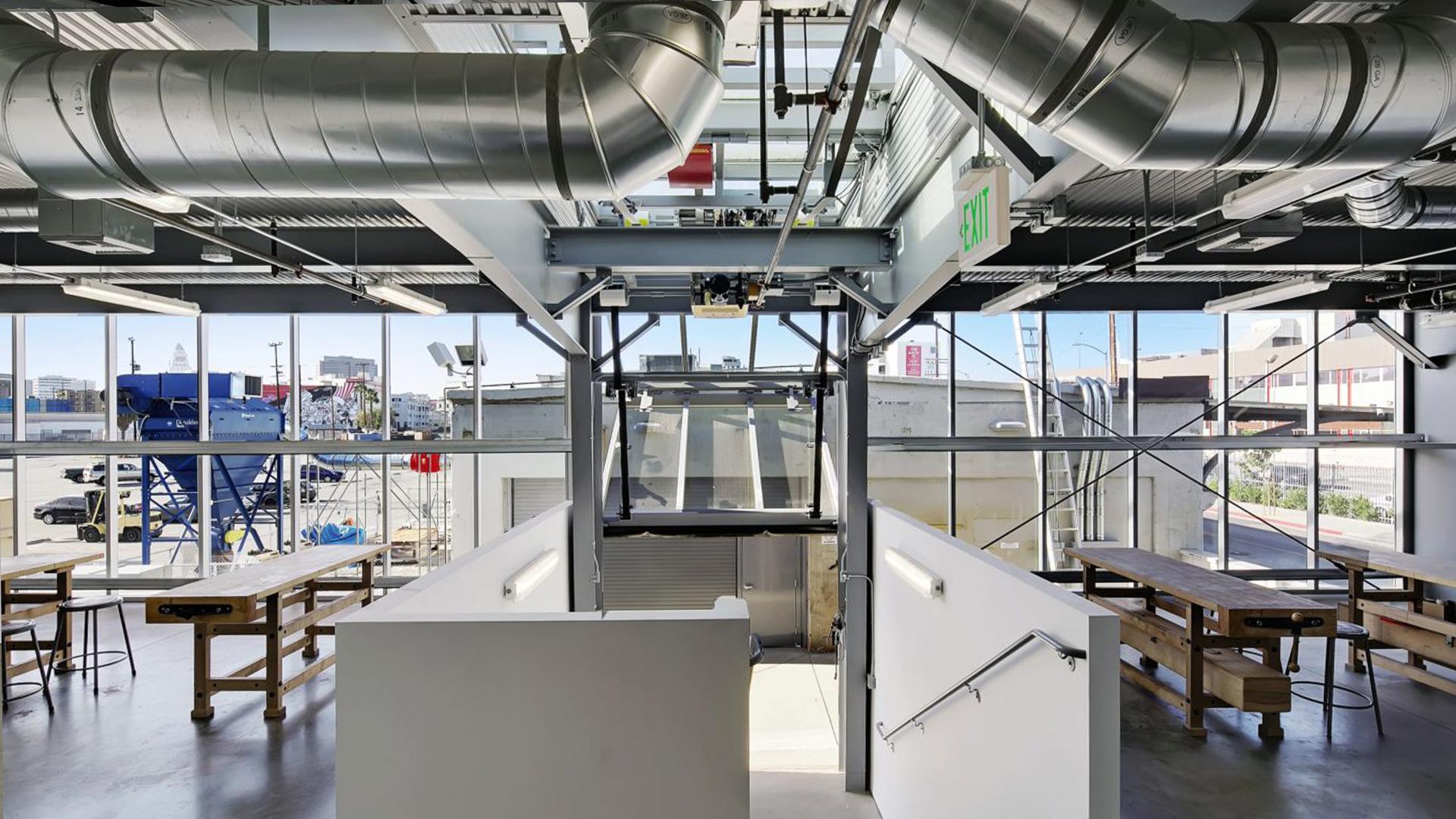 Collaborative learning space with worktables, exposed steel framing and floor-to-ceiling windows.