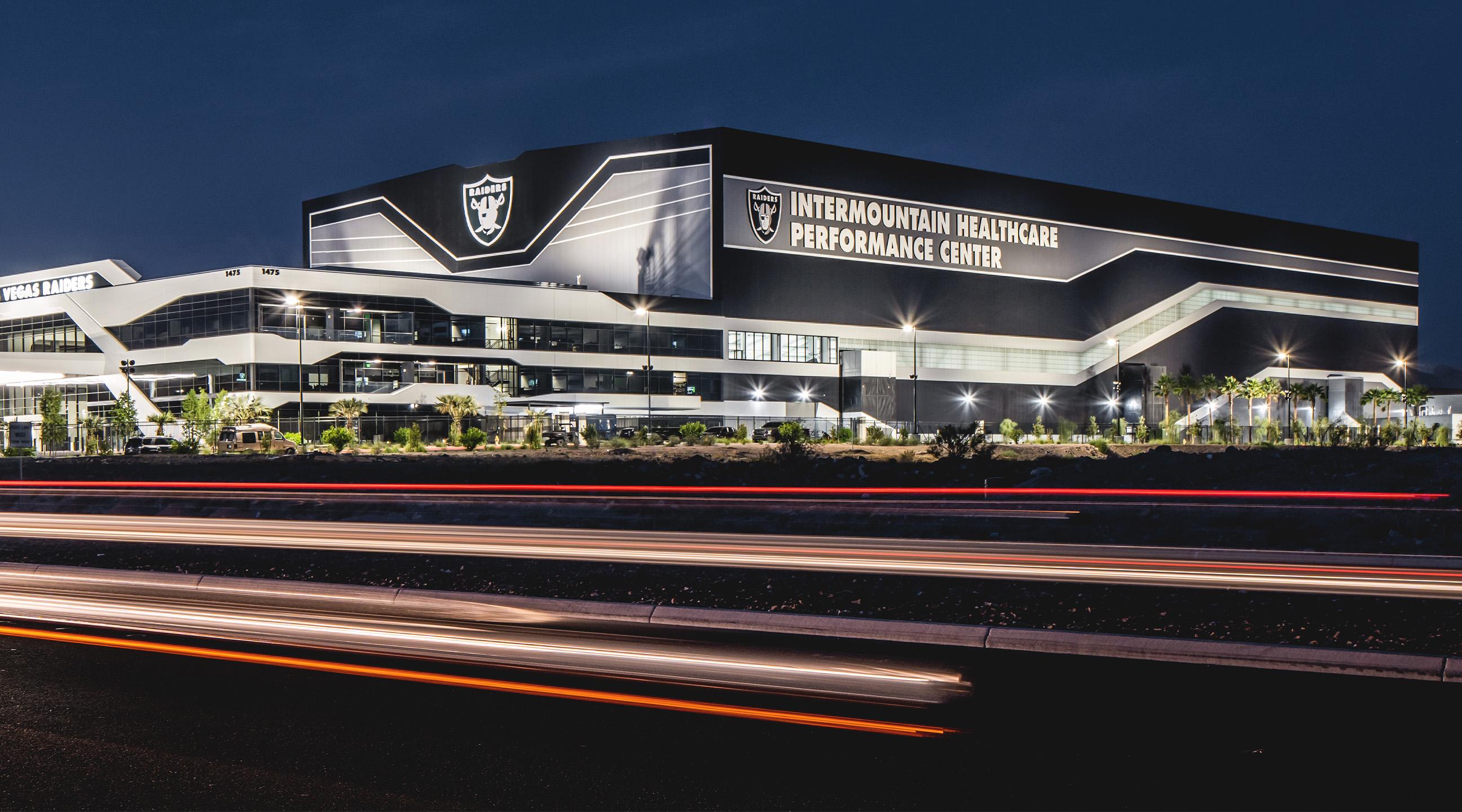 Las Vegas Raiders performance center at night with illuminated metal facade and angular rooflines