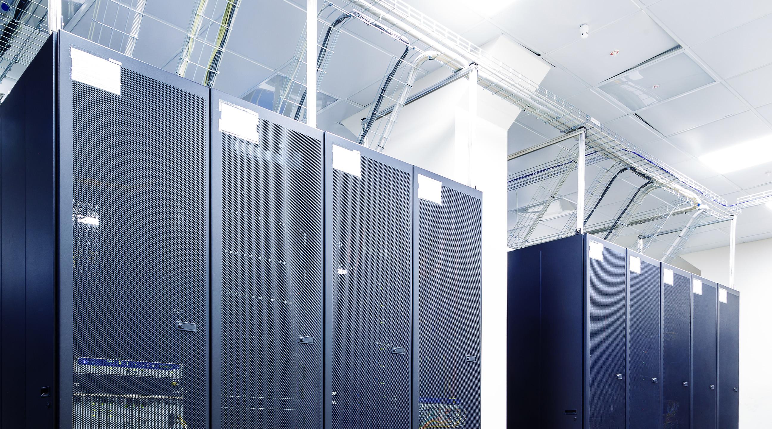 High-density data center interior with aligned server racks and integrated cooling and power systems—engineered to deliver continuous uptime, controlled environments, and predictable performance for mission critical operations.