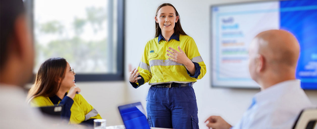 A female employee presenting to others in a meeting room