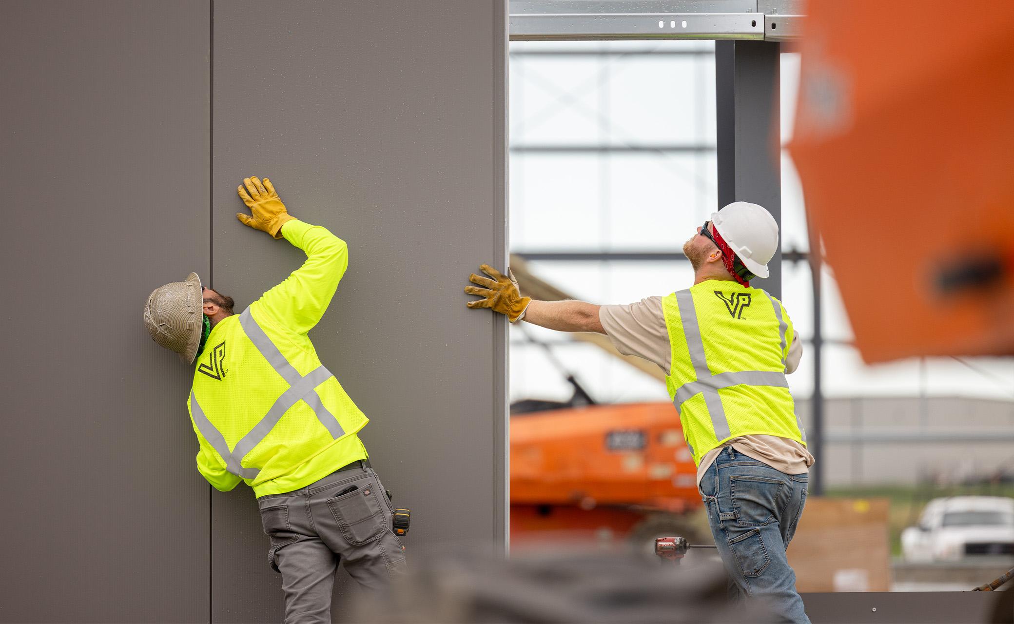 Construction professionals installing architectural wall panels, demonstrating coordinated field execution and precision alignment during building envelope construction.