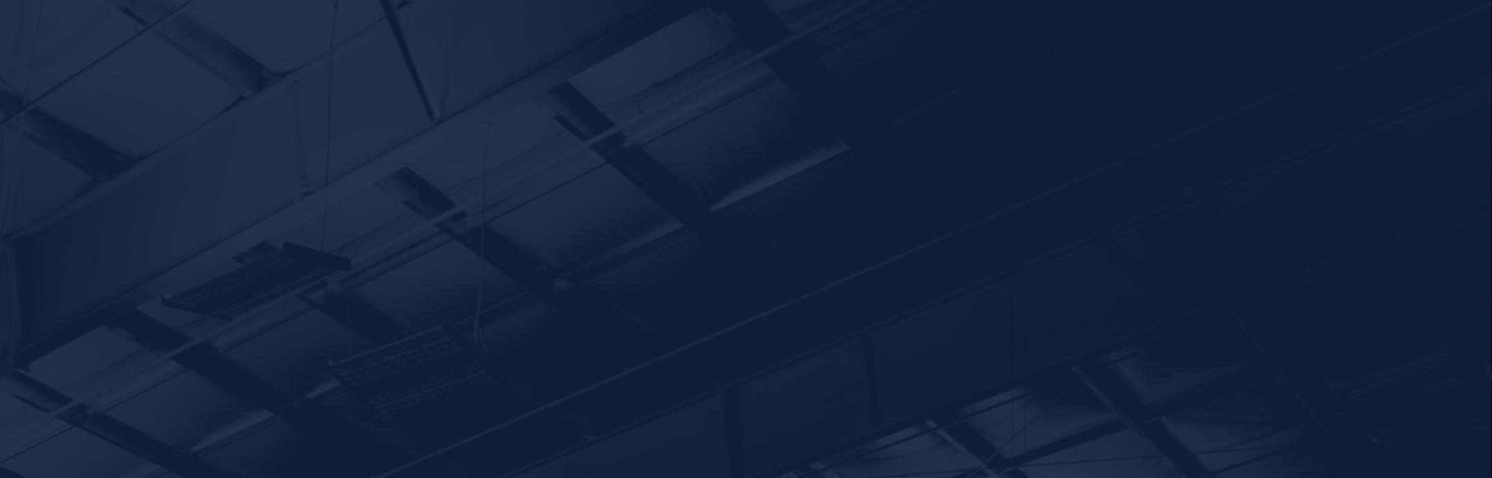 Dark blue, high-contrast header image featuring an abstract, low-light view of a steel building roof structure, emphasizing engineered framing, depth, and structural precision.