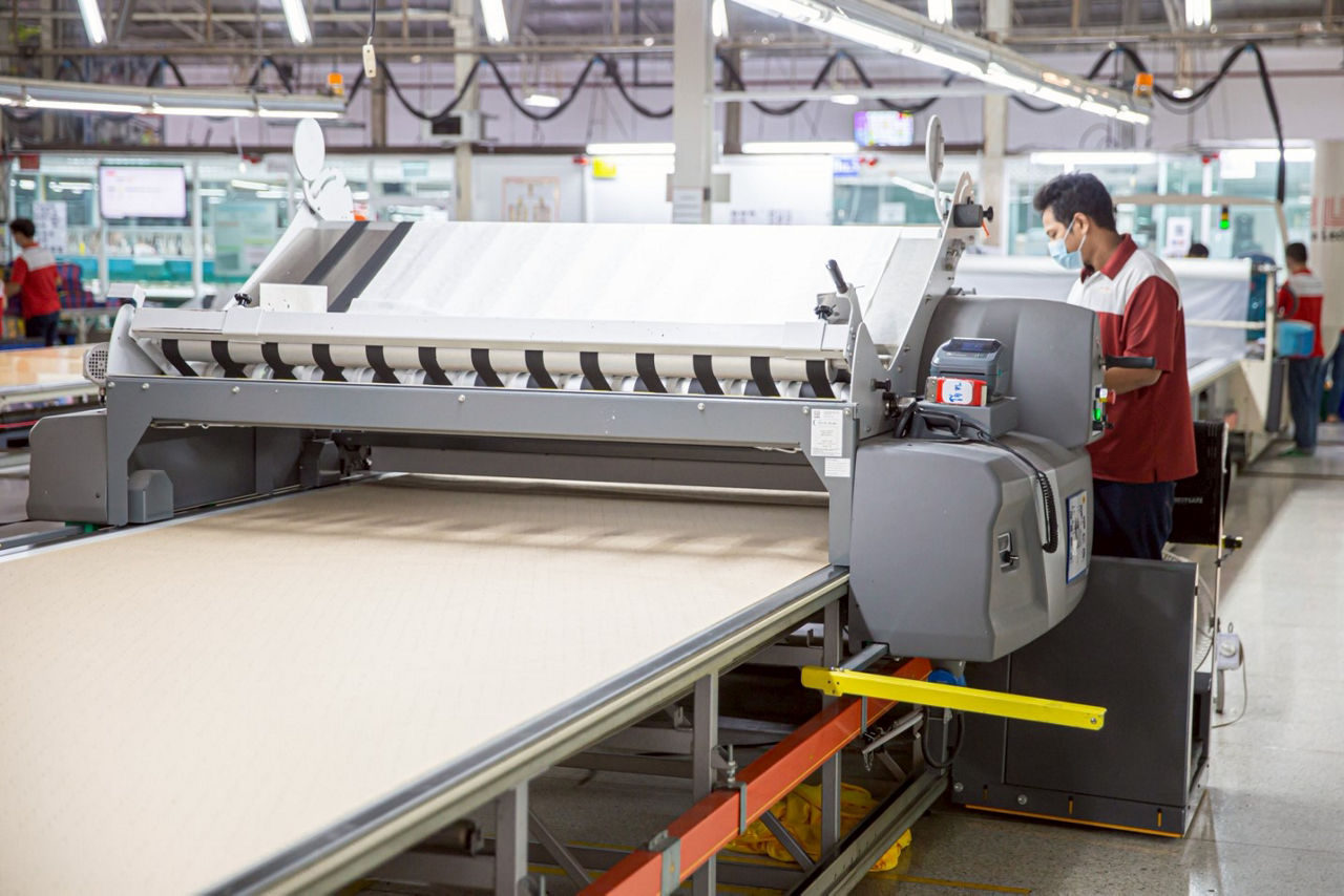 textile factory with worker and machine in the foreground