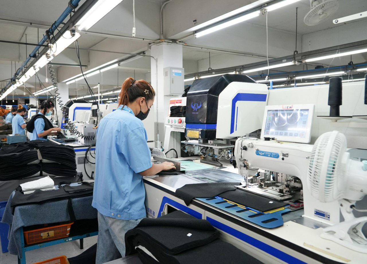 textile factory with workers at computerized machinery