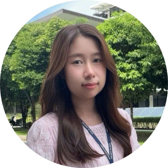 ID photo of Supatsara Klinjaeng a young woman with long bleached hair and black eyes wearing a pink round collared puffy top and an ID lanyard with trees and an office building in the background