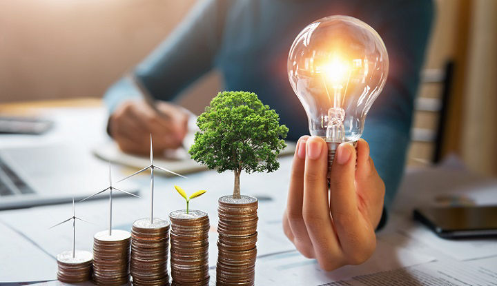 businessman holding lightbulb with turbine and tree grow on coins. concept saving energy and finance accounting