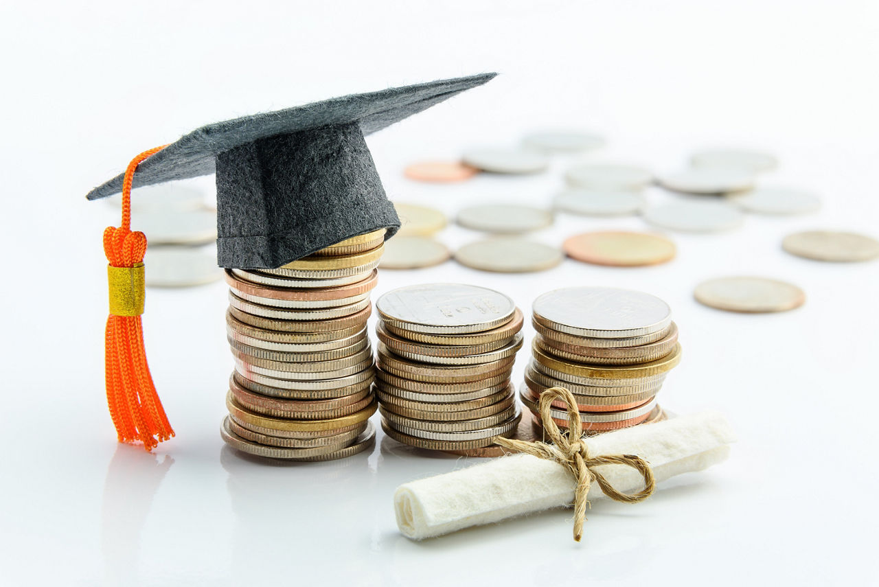 Money cost saving or money reserve for goal and success in school, higher level education concept : US dollar coins / cash, a black graduation cap or hat, a certificate / diploma on white background.