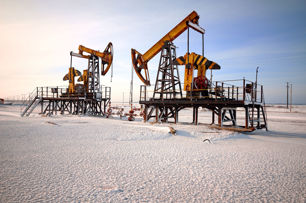 Oil pump cold winter and snow. Back light, white cloudy and blue sky background, sunlight