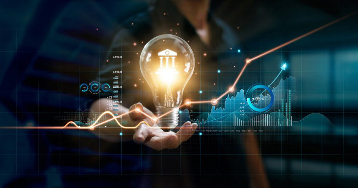 Businessman holding creative light bulb with growth graph and banking icons. Financial innovation technology develop new products and services that enhance successful and profit in global business.