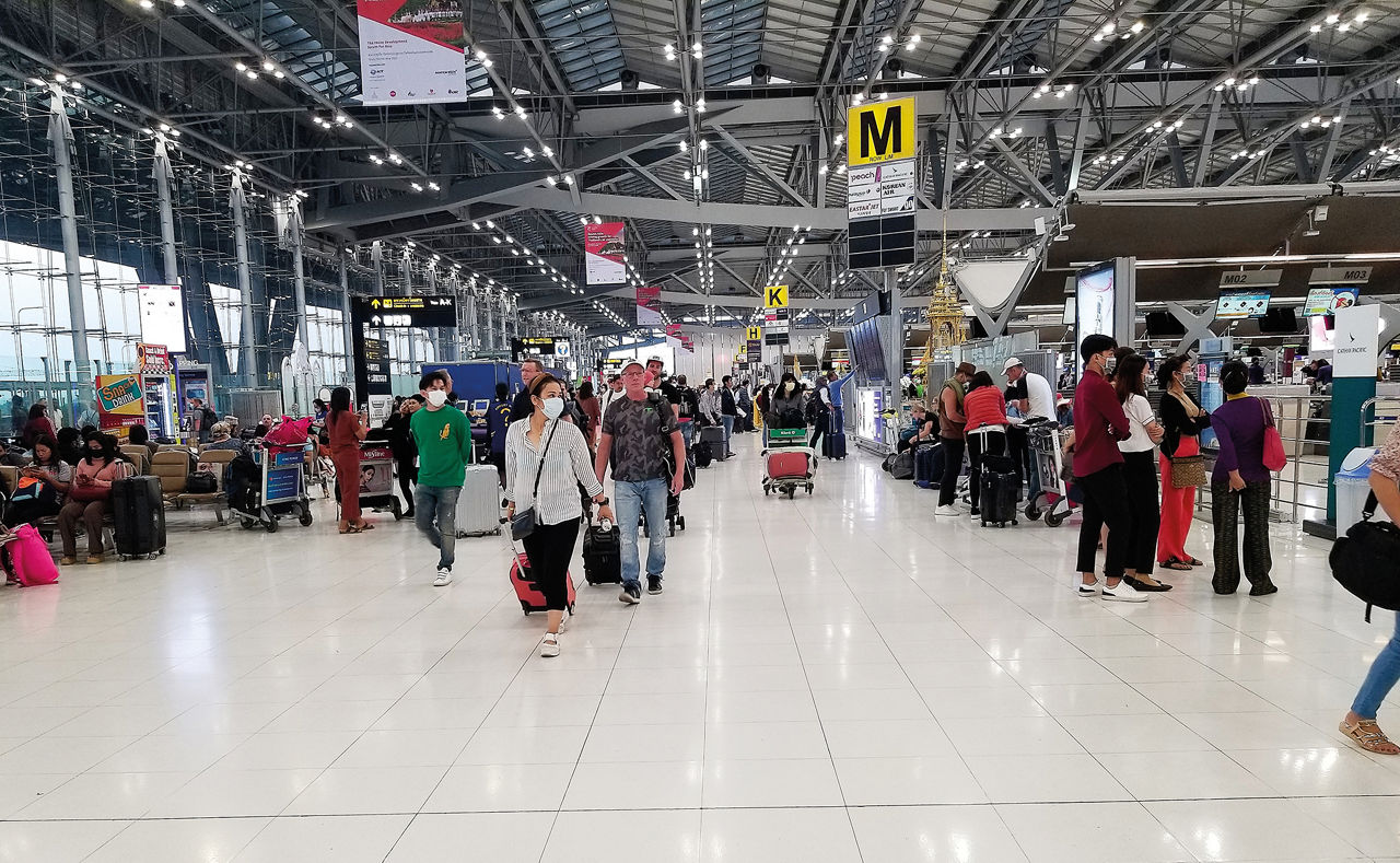 Bangkok, Thailand, February 12, 2020-travelers  at Bangkok International Airport walking with luggage, wearing surgical masks following the Coronavirus outbreak.