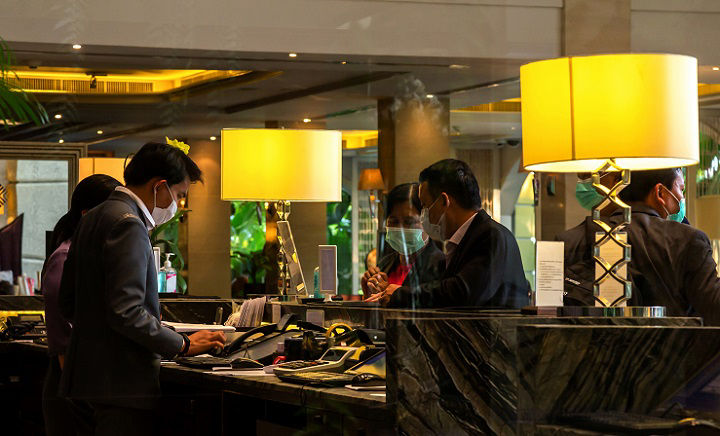 Bangkok, Thailand - March 4, 2020 : asian receptions and business travelers check-in in hotel lobby front desk are wearing hygiene mask to protect from outbreaking of coronavirus or covic 19.