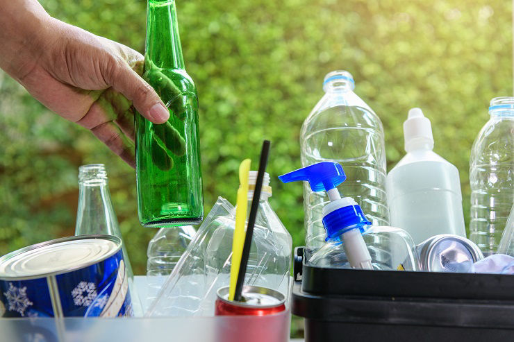 Close up hand dropping glass and plastic bottle into the bin for separating recycle materials from the garbages. Reducing waste by following the green concept. Recycling process.