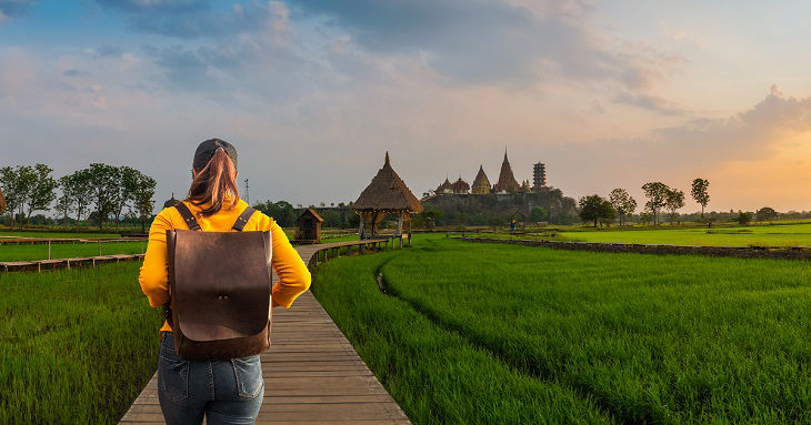 Wide Panorama traveler woman in nature view scenic landscape green rice field at beautiful sunrise, Attraction famous landmark tourist travel Kanchanaburi Thailand vacation, Tourism destination Asia