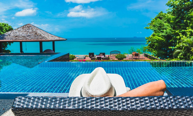 Man traveler relaxing near luxury swimming pool and sea beach, Phuket, Travel in Thailand, Summer vacation concept