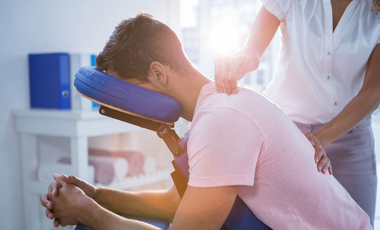 Physiotherapist giving back massage to a patient in clinic