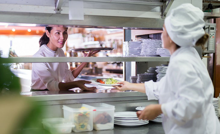 smiling female waiter geting order from chef in restaurante; Shutterstock ID 1842503818; purchase_order: BOT; job: ; client: ; other: 