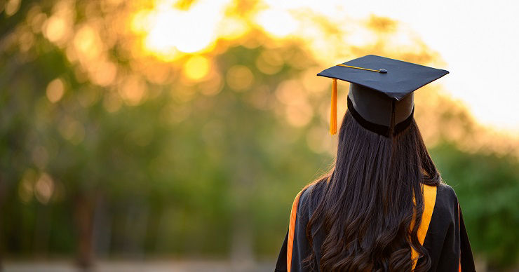 Female graduates wear black gowns and yellow tassels waiting to attend the commencement ceremony at the university.