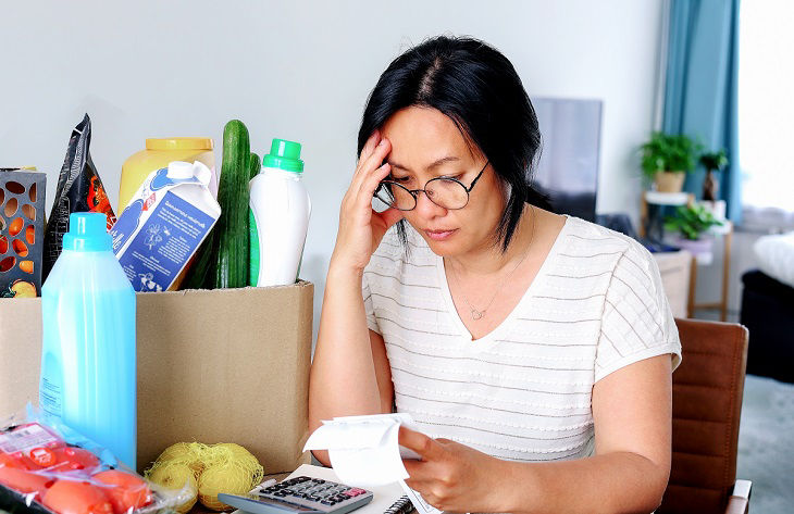 Woman headache stress inflation crisis high cost in gas electric energy holding receipts from supermarket with calculator by rising grocery prices and surging cost as an inflation financial crisis.; Shutterstock ID 2162437299; purchase_order: BOT; job: ; 