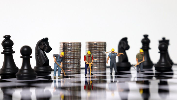 Pile of coins and miniature people on the chessboard.