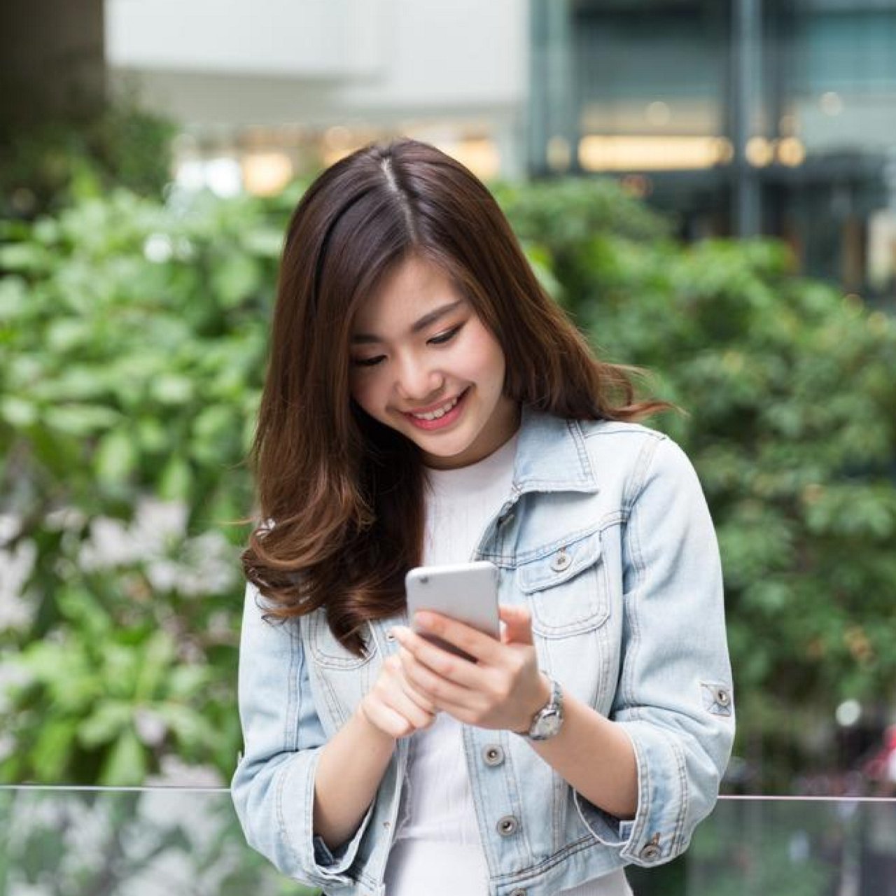 A woman sitting in a corner of a living area with a laptop smiling.