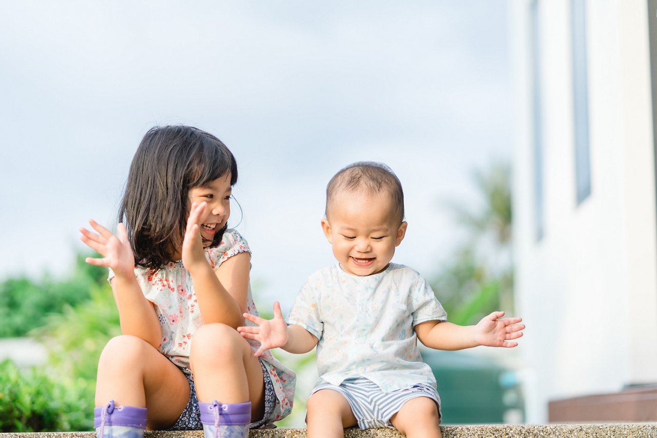 Little sister playing with her baby brother.Toddler kid meeting new sibling. Cute girl and baby boy clapping hands at home in Japan.Family with children at home. Love, trust and tenderness.