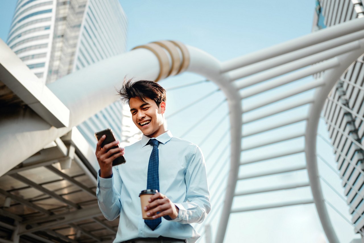 Portrait of a Smiling Young Asian Businessman Using Mobile Phone in the City 