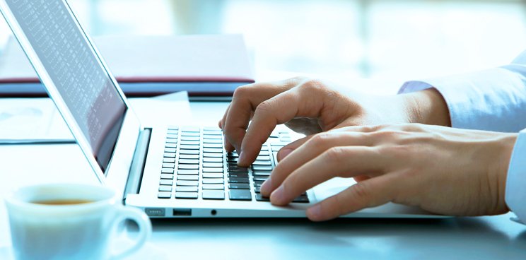 Hands typing on a laptop keyboard.