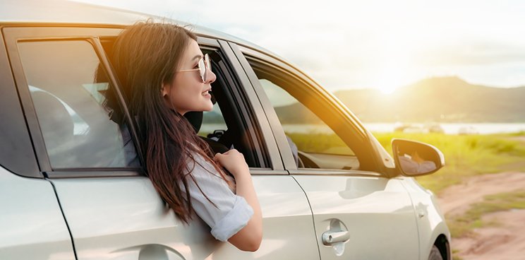 A woman happy as she leans out a car window
