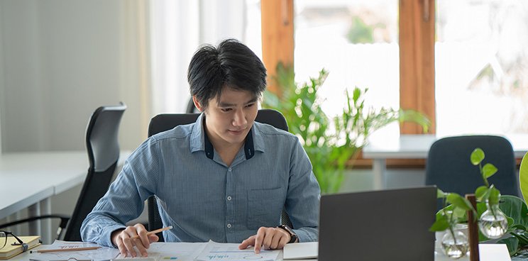 A man working in an office setting with his laptop.