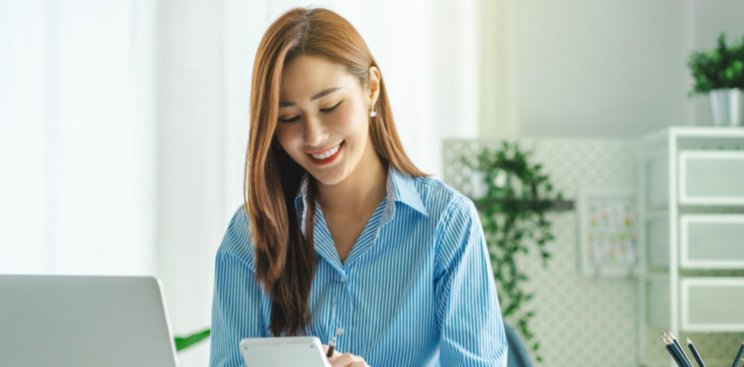 A woman fixing her documents with a tablet in front of her.