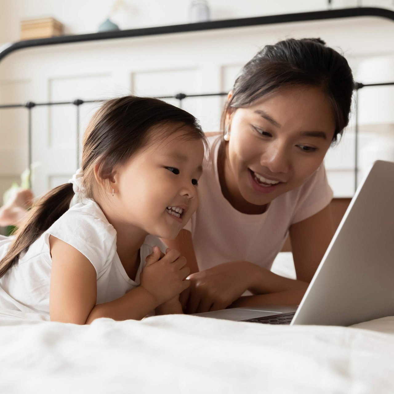 Mother and daughter on the bed, looking at laptop