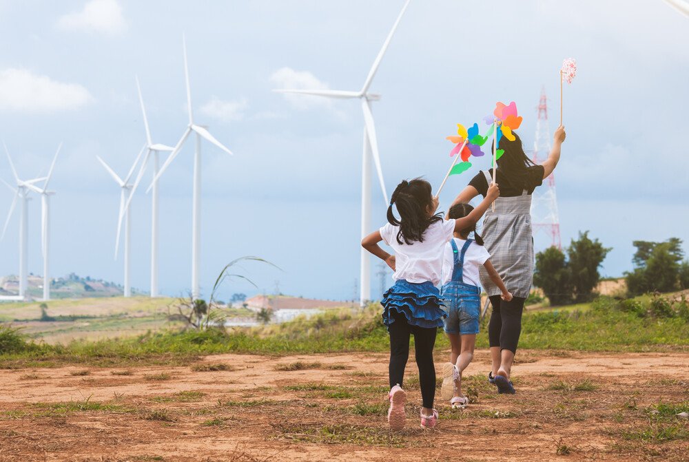 A group of young girls marching with their colorful pinwheels toward a strip of windmill.