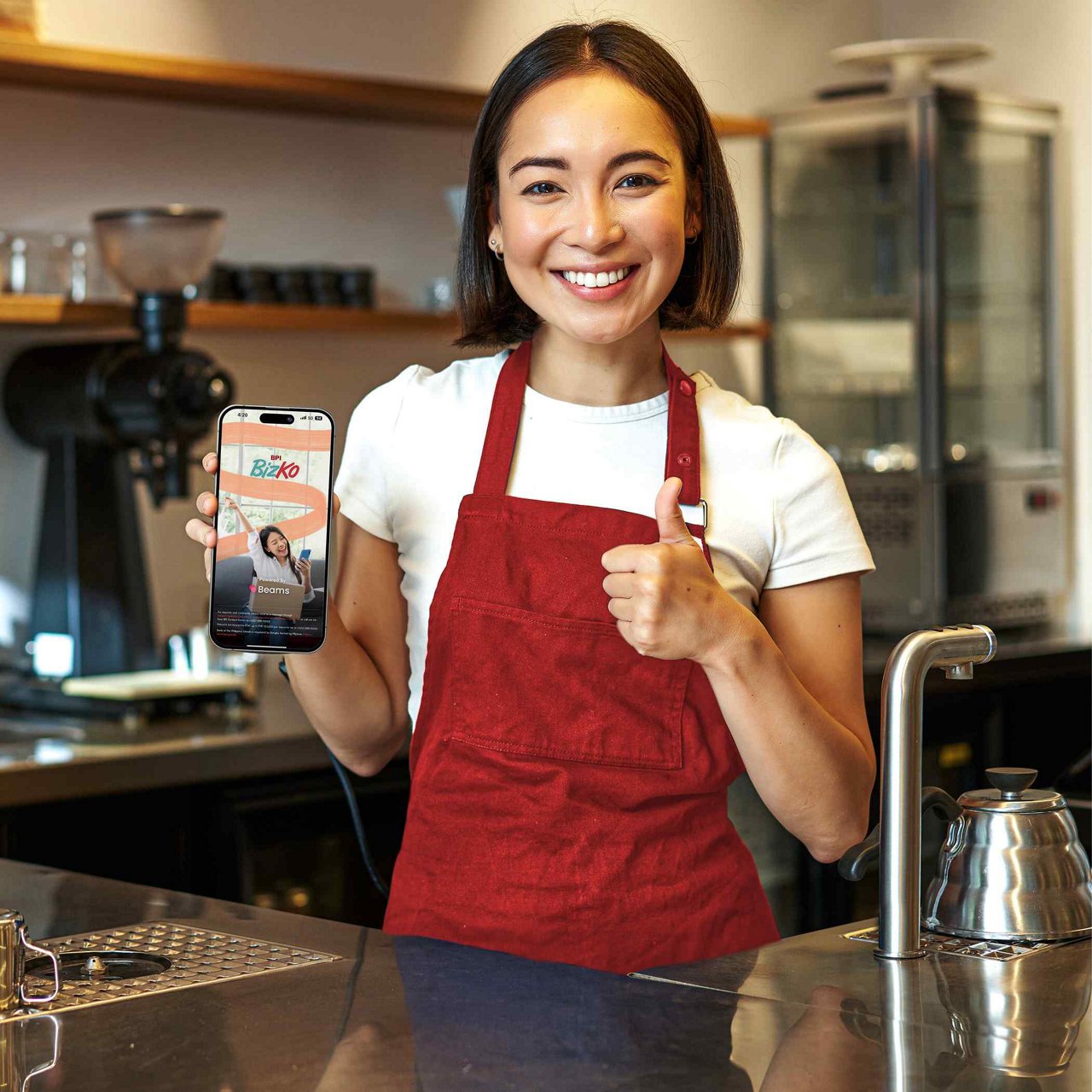 A woman in her café smiling as she looks at her tablet