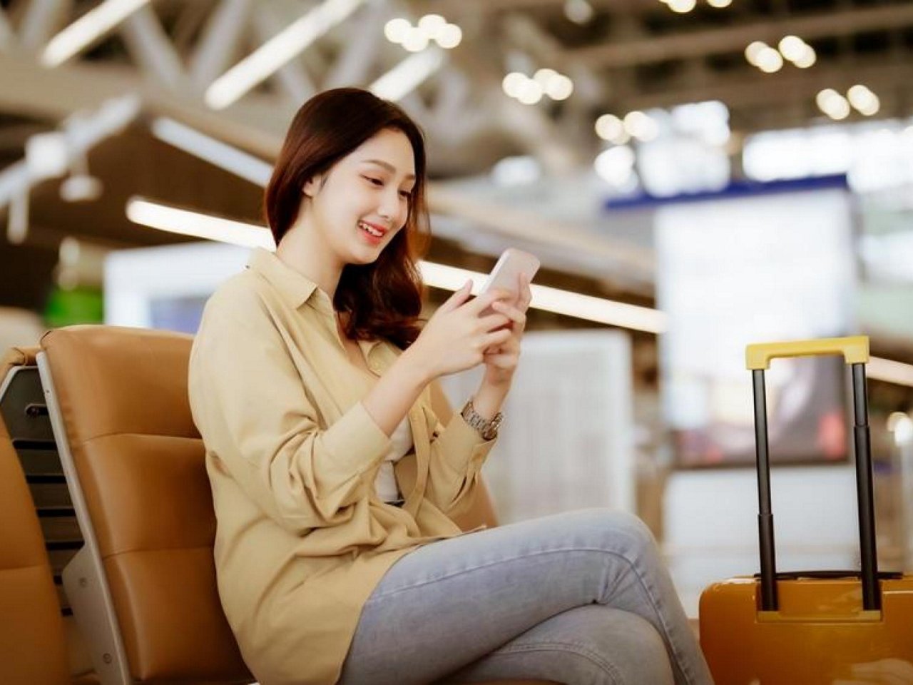 A smiling girl holding her phone and card.