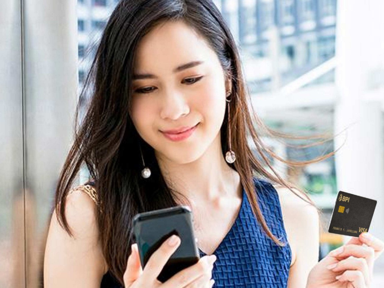 A smiling woman holding her phone and card.