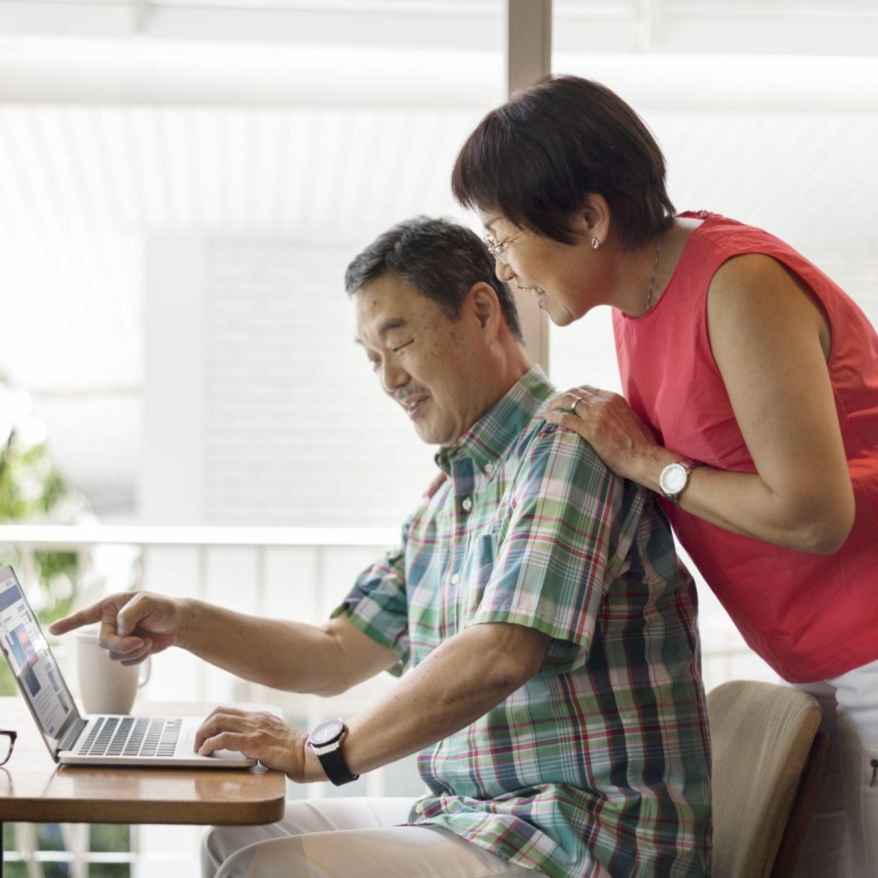 A woman discussing to an elderly couple with a laptop in a living room setting.