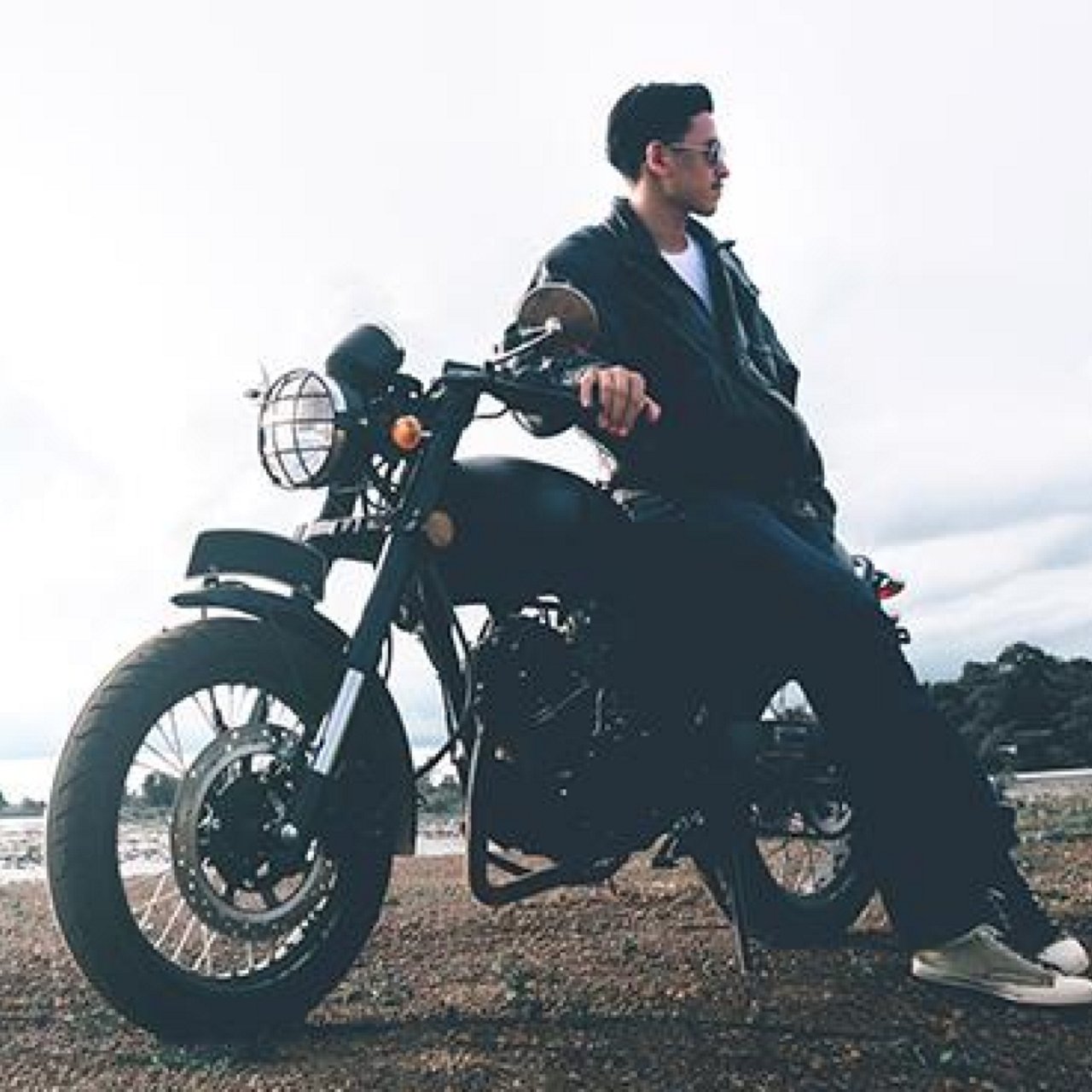 A man leaning on his bike on a dirt road
