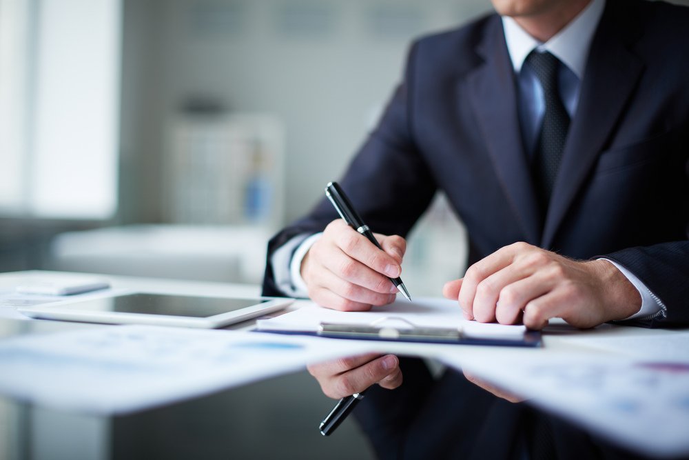 A man reading printed terms and conditions with a pen in his hand.