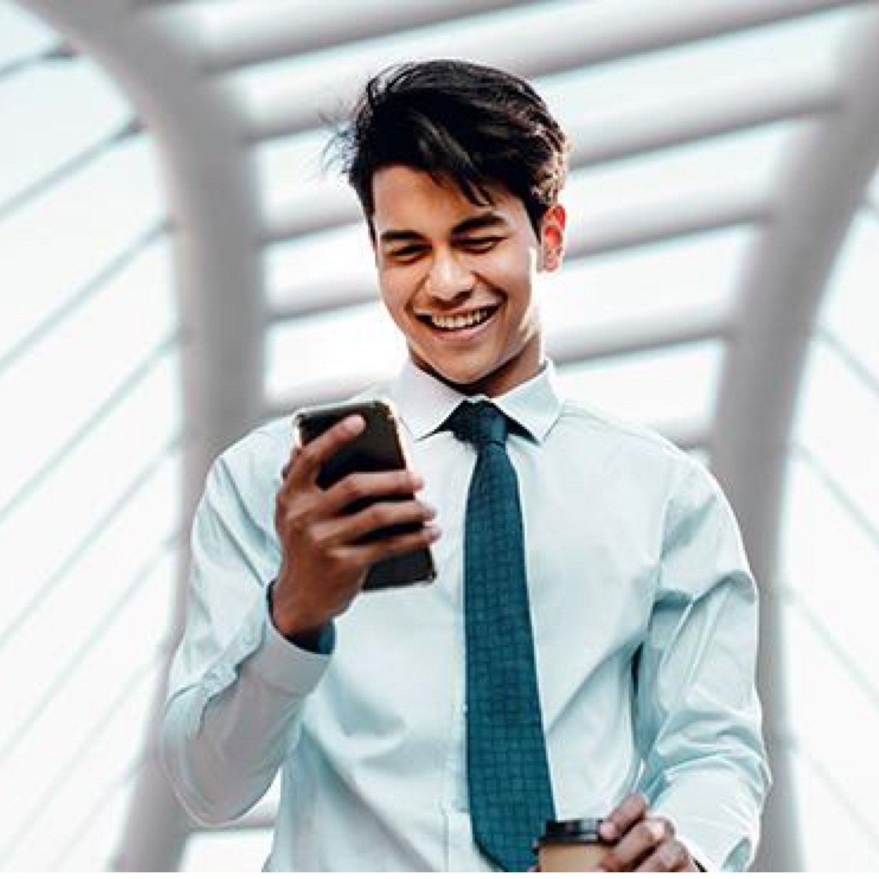 A man smiling as he looks at his mobile phone.