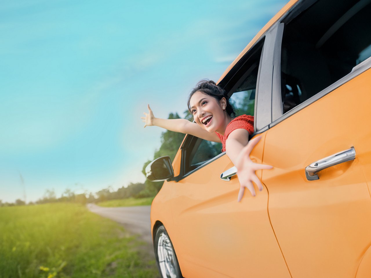 A woman happy as she leans out a car window