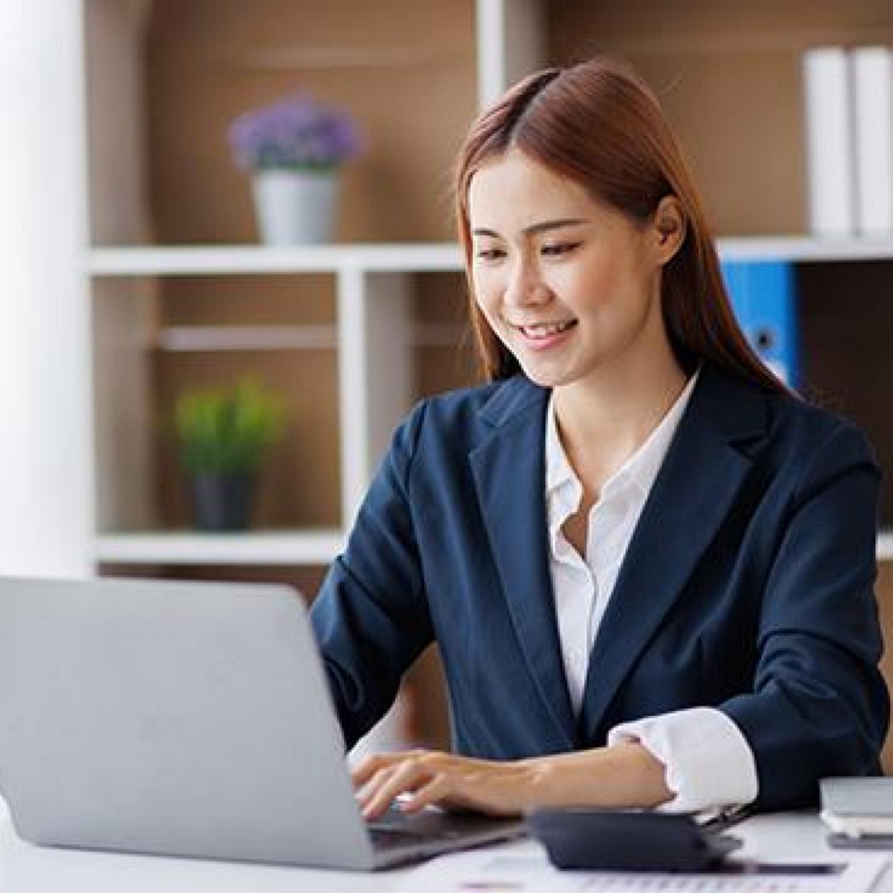 A woman looking at a laptop in an office setting.