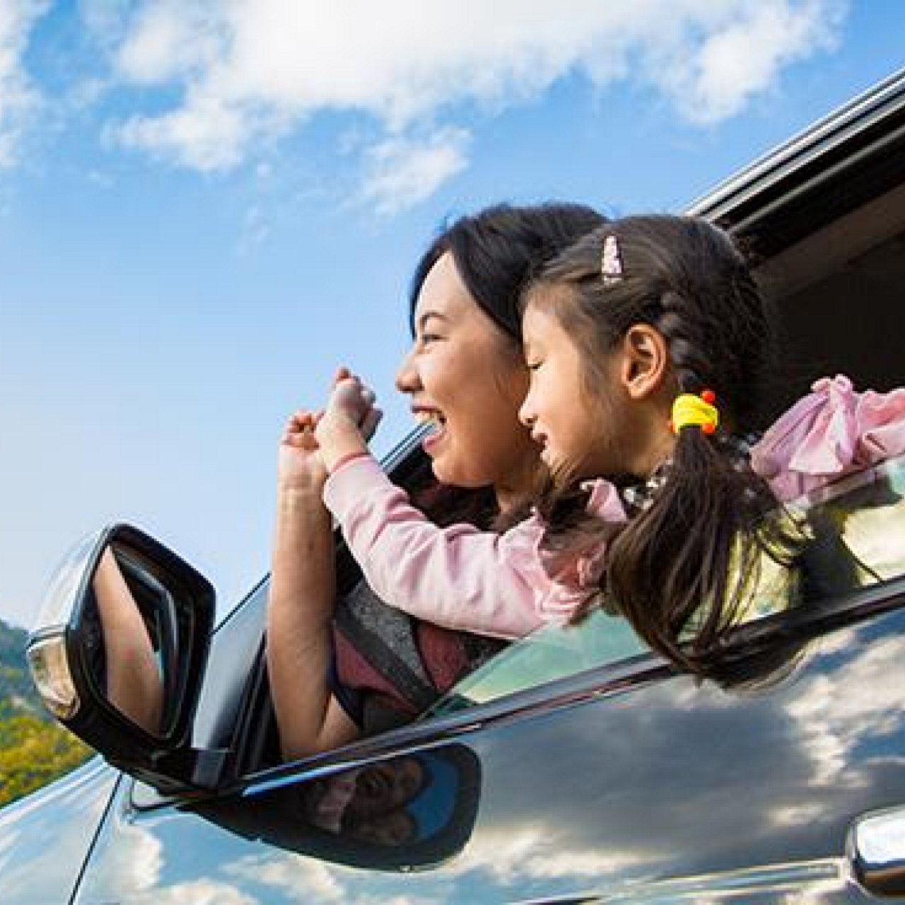 A mother and child leaning out a car window