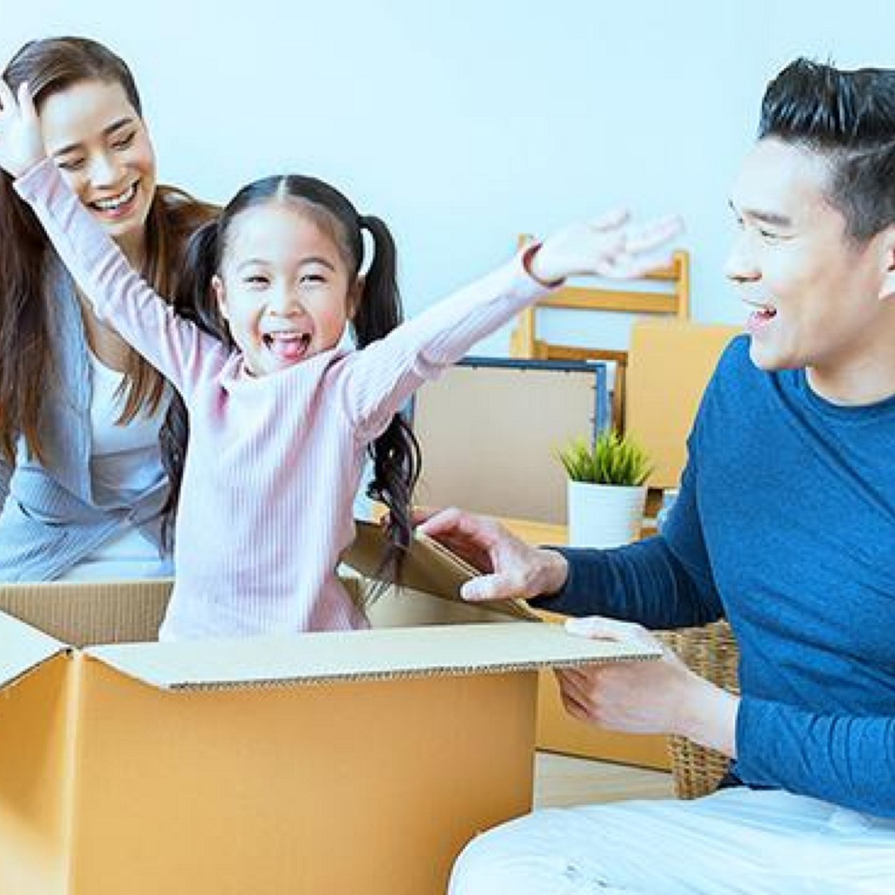 A happy little girl bursts out of a box to surprise her parents as they move in to a new house