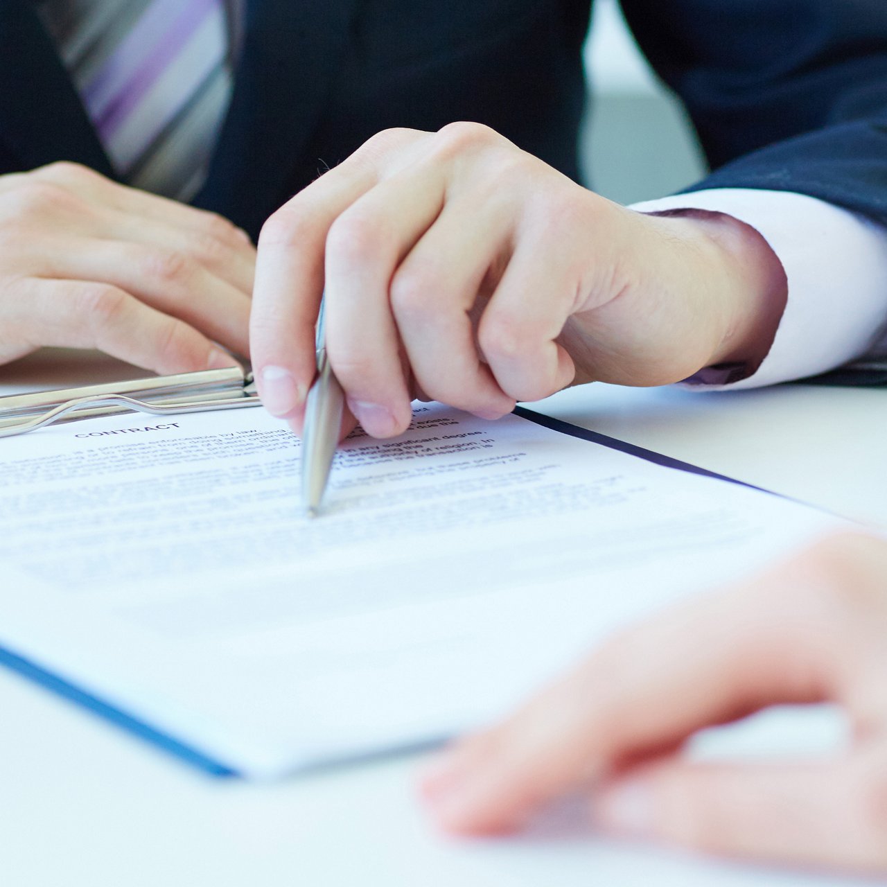 A man reading printed terms and conditions with a pen in his hand.